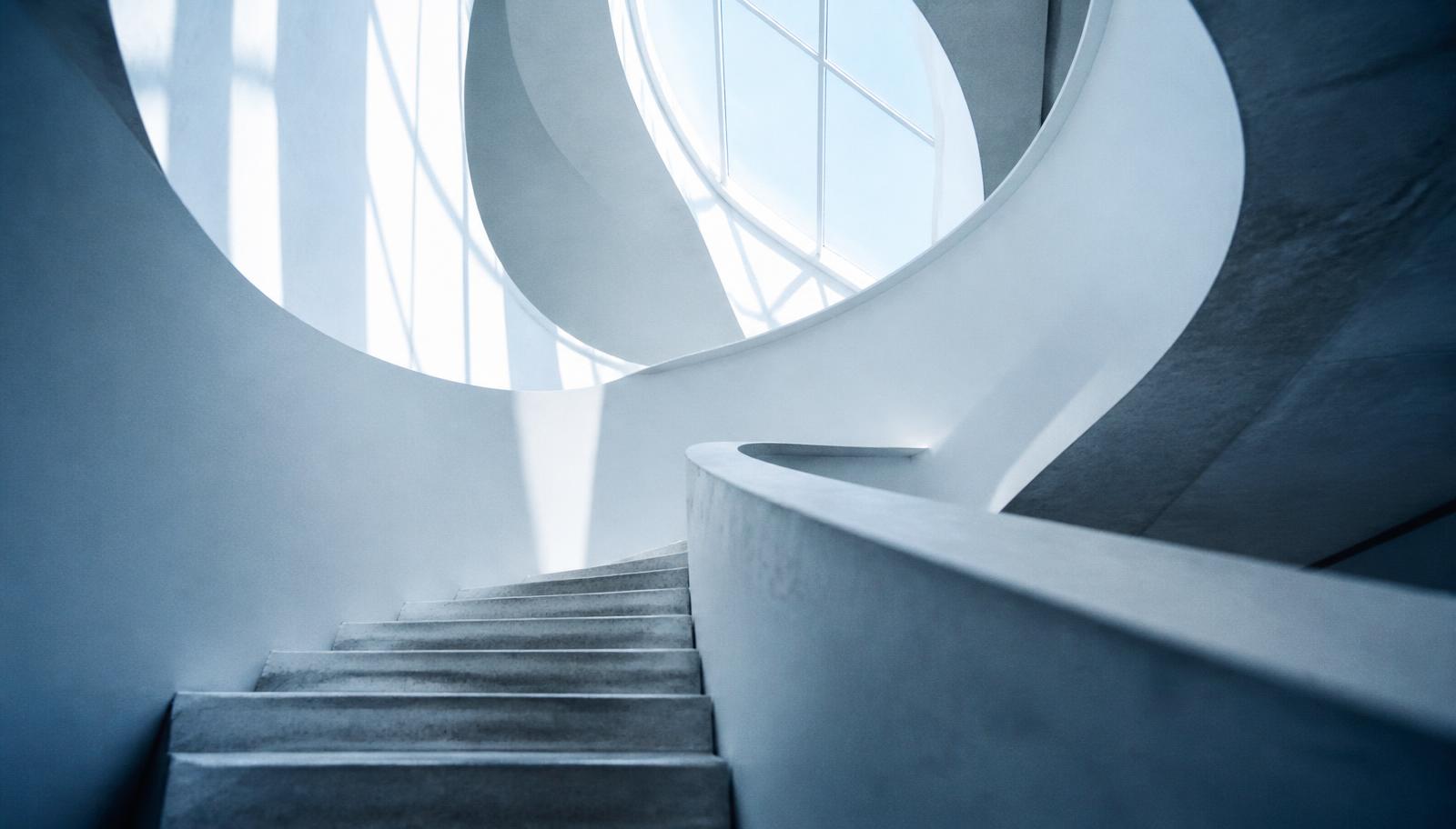 Looking up a pale spiral stairwell toward a skylight